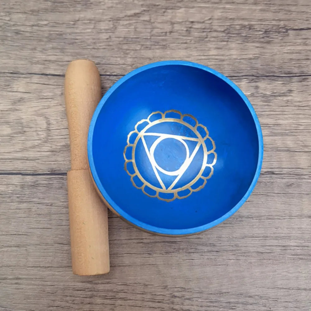 Blue singing bowl with a gold symbol on a wooden surface